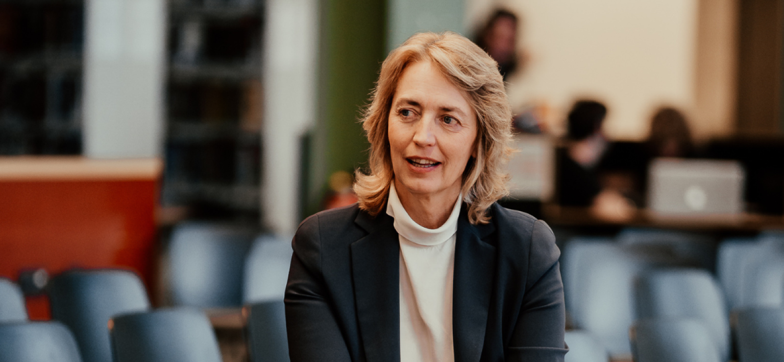 Kristl Vonck zit in een zaal met stoelen op de achtergrond
