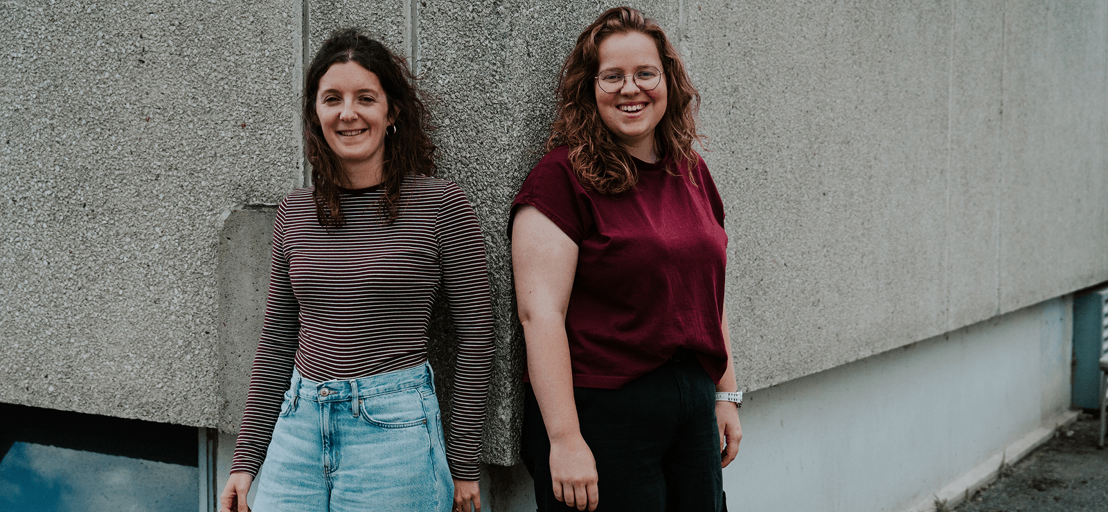 Twee jonge vrouwen leunen tegen de hoek van een home van UGent.