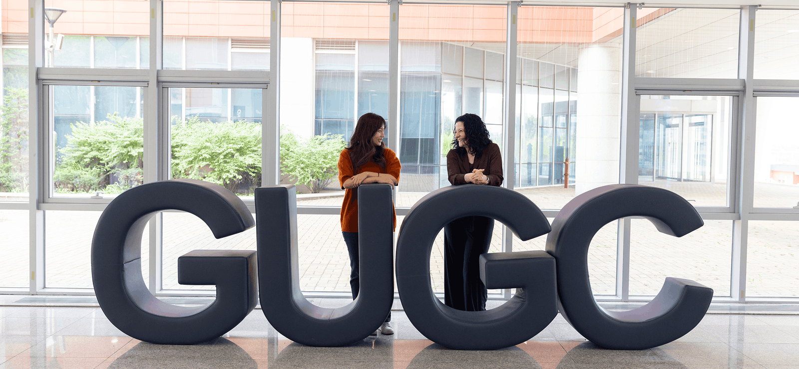 Mara and Terry leunen op het logo van GUGC en kijken naar elkaar.