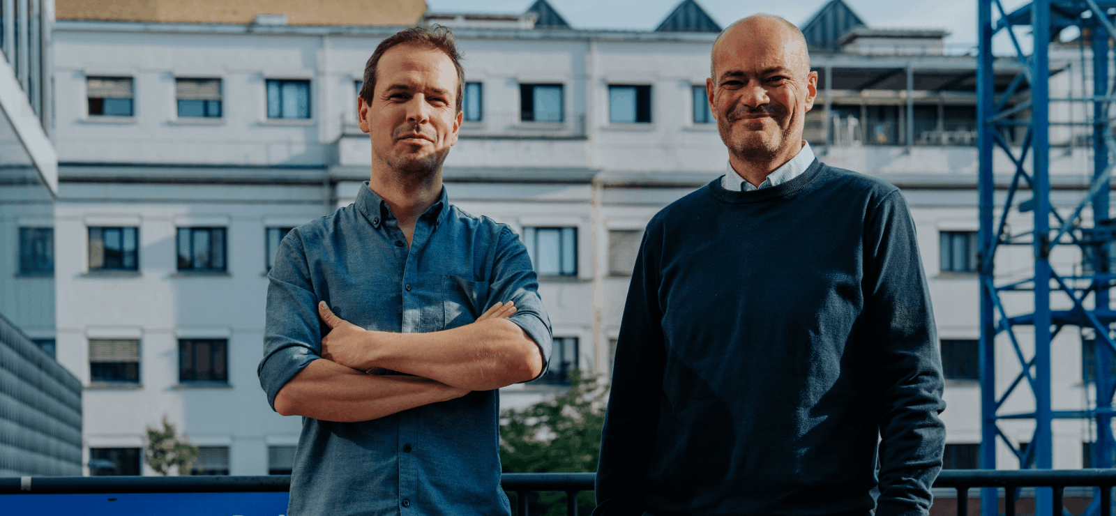 Tristan en Jeroen glimlachen voor de ingang van een auditorium.