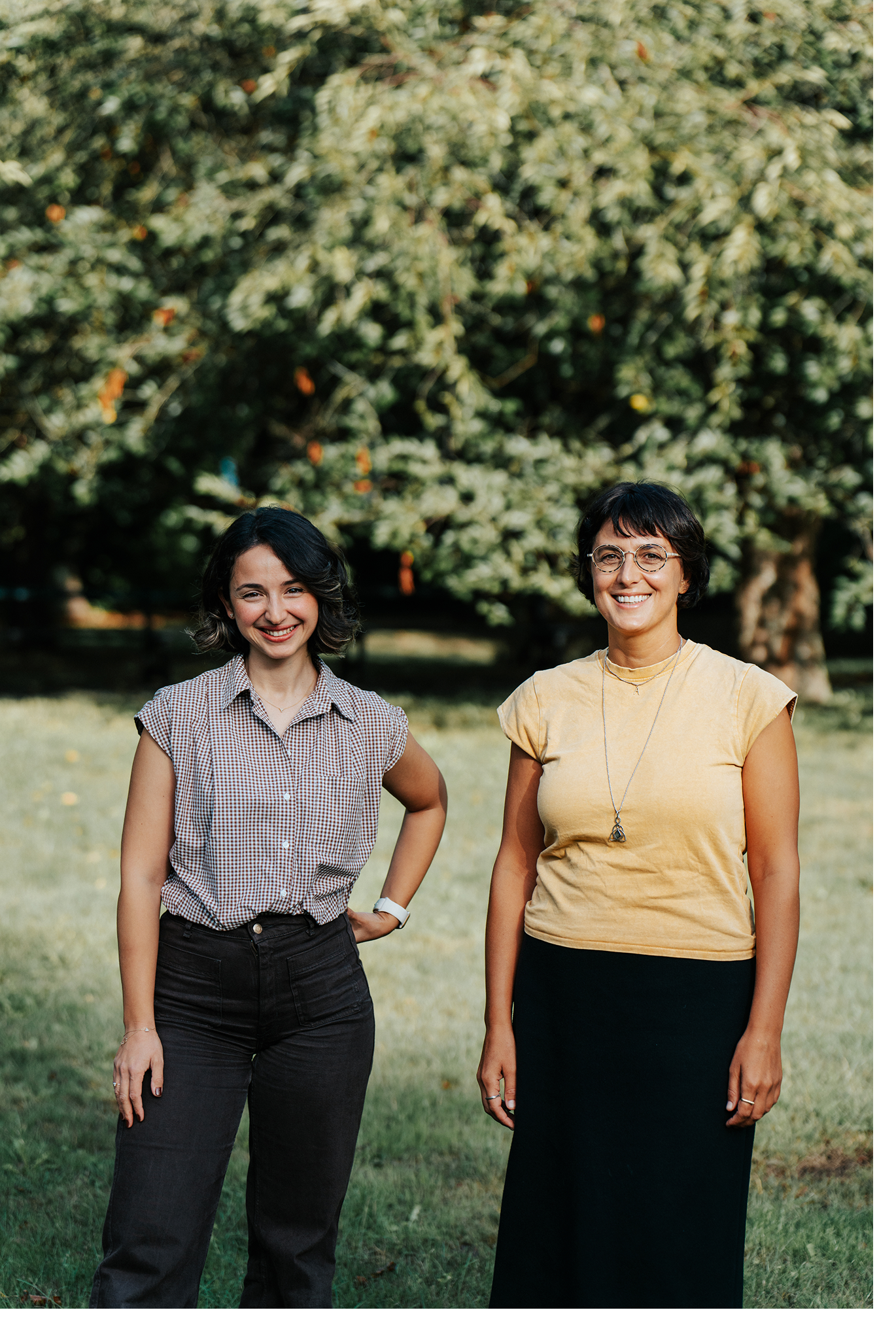 Francesca en Melis staan naast elkaar in een tuin met bomen
