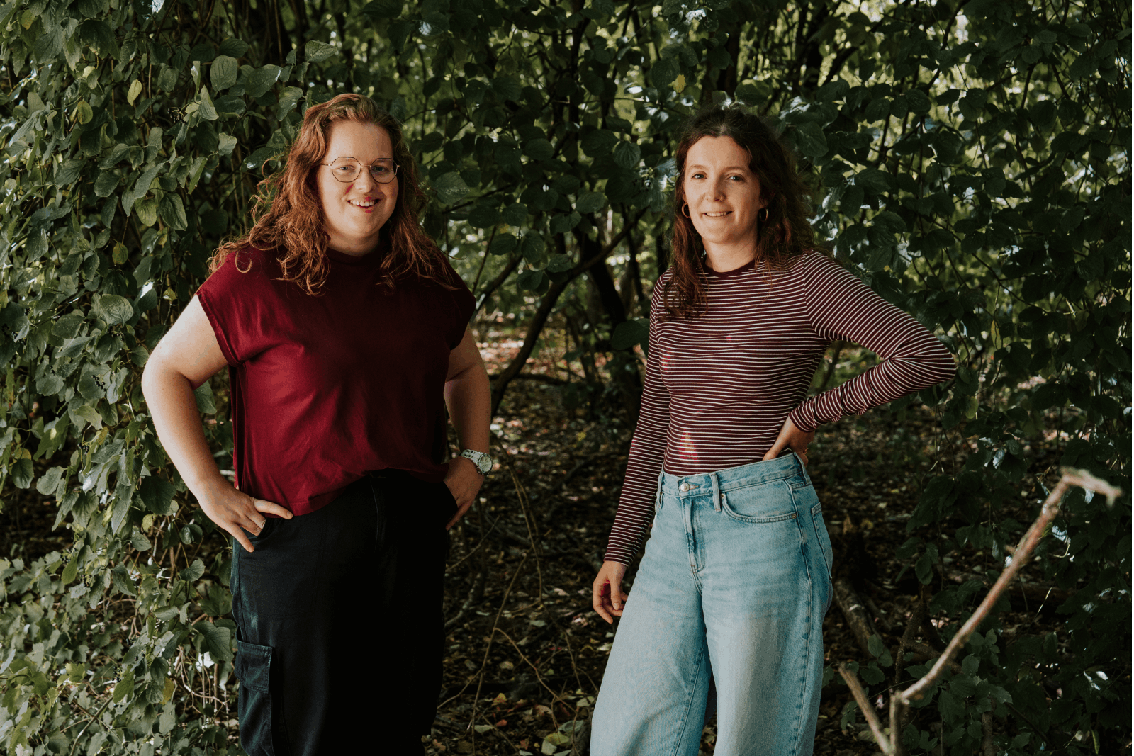 Twee jonge vrouwen poseren voor een struik.