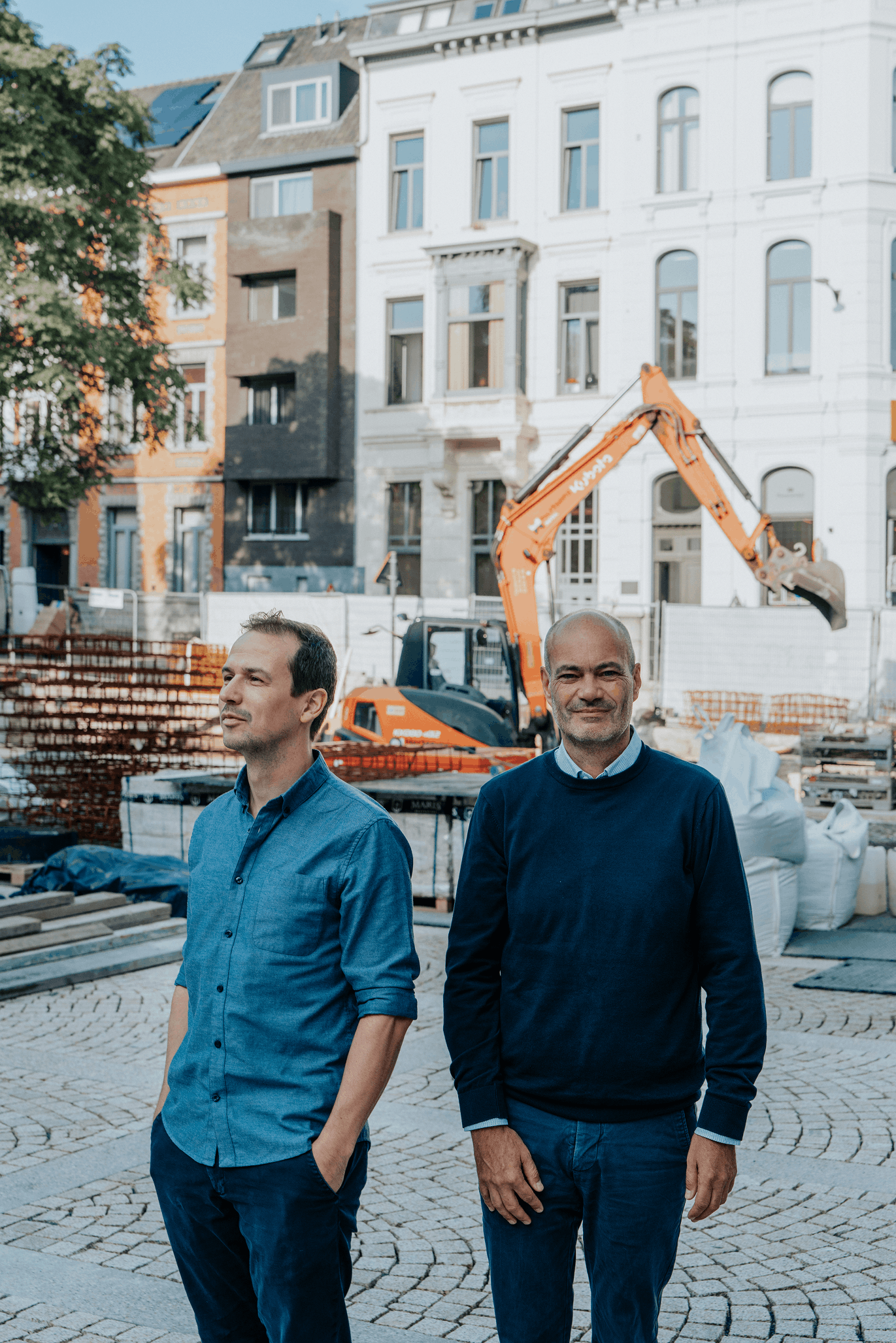 Twee mannen, Tristan en Jeroen, staan voor een graafmachine op een werf in Gent.