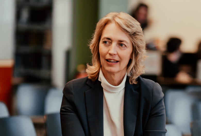 Kristl Vonck zit in een zaal met stoelen op de achtergrond