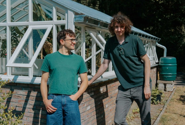 Victor en Leonardo leunen tegen een serre in de tuin.