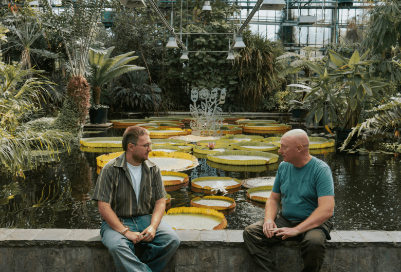 Lars en Herbert voeren een gesprek met elkaar naast reusachtige lelies
